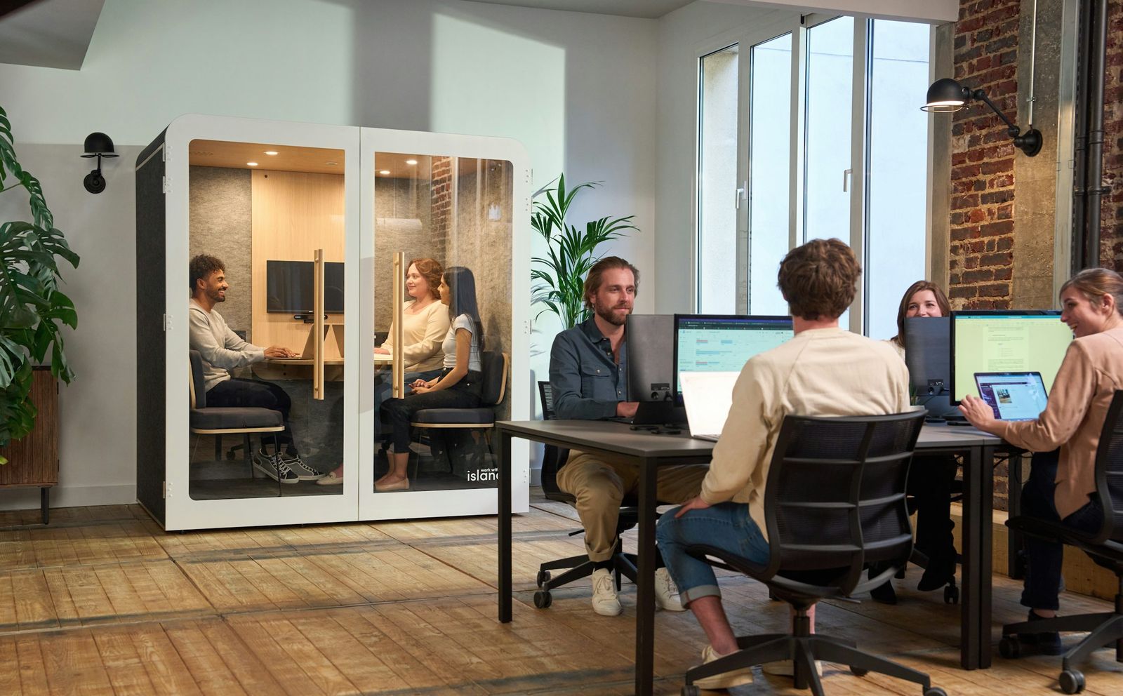 Plateau de bureaux parisien : postes de travail, cabine acoustique, grandes fenêtres.