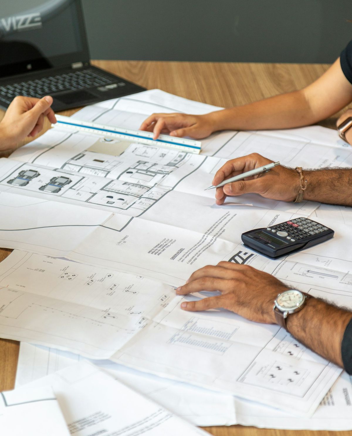 Mains posées sur des plans d'aménagement imprimés.